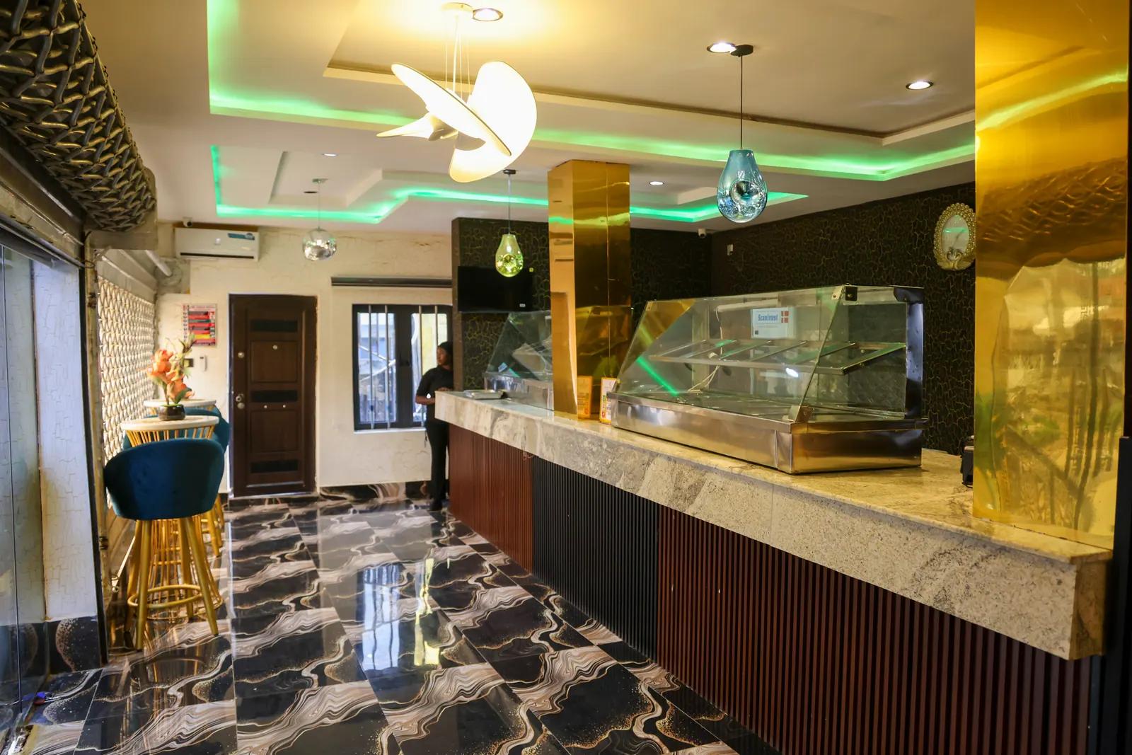 The restaurant counter, under green and gold lighting
