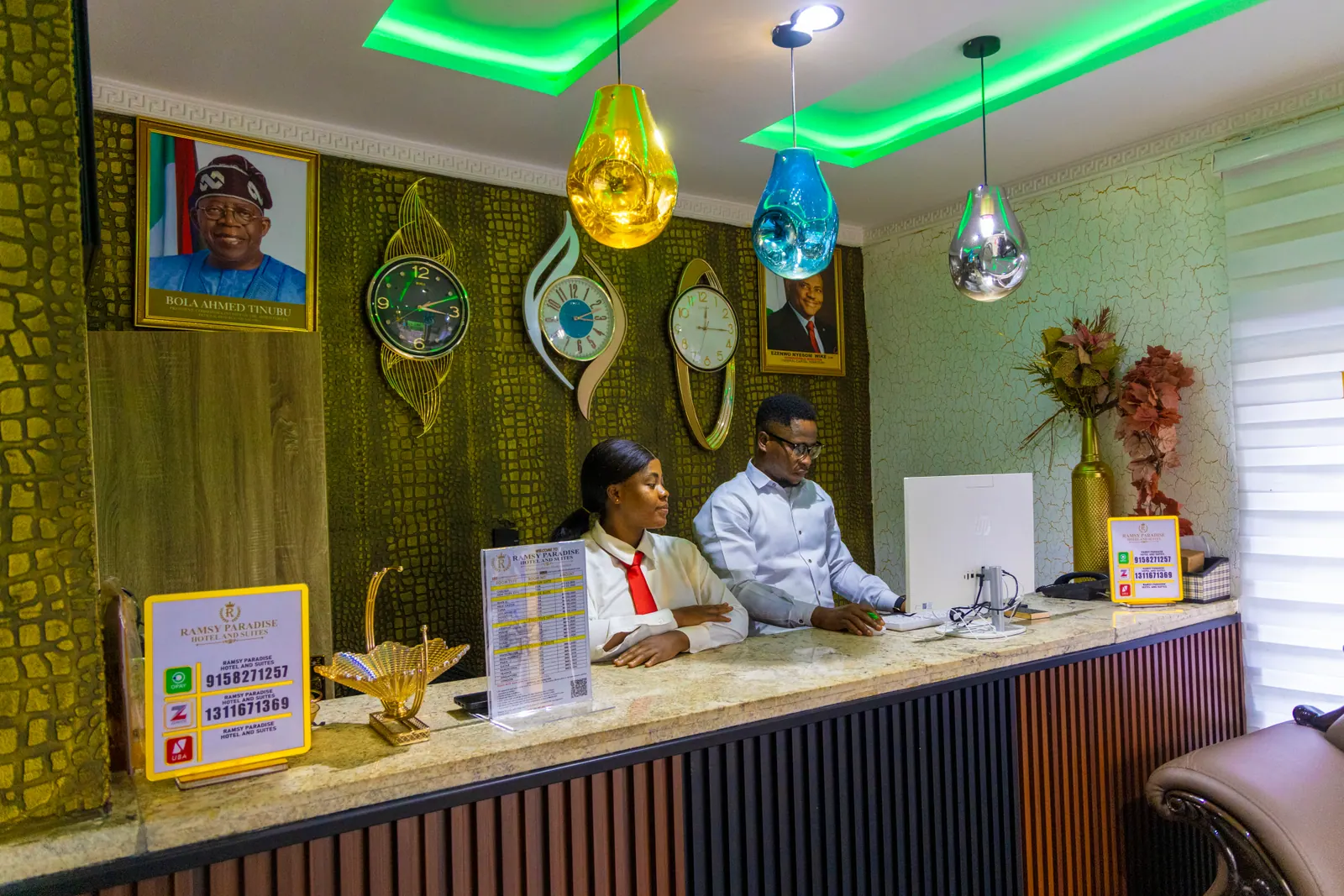 The reception desk in green light, with the hotel's tariff card on the counter
